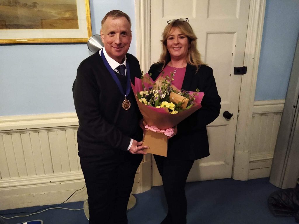 President Ashley Price presenting a bouquet of flowers to Immediate Past President Clare Crouch